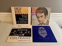 Four vinyl albums laid out showing front covers of Billy Joel The Nylon Curtain, Neil Diamond's Greatest Hits, Miles Davis & John Coltrane concert album, and Big Country The Crossing.