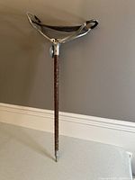 Full view of the antique hunting stool showing metal tripod seat and carved wooden folding leg.