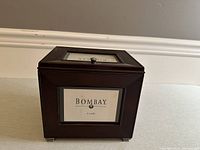 Front side view of the wooden photo box with a glass photo frame insert showing the Bombay Company brand label.