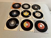 Overview photo showing all 9 7 inch vinyl records laid out with visible labels and sleeves in various conditions.