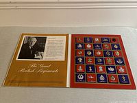 Photo showing the introductory page and cover of the collection 'The Great British Regiments' with a photo and text on the left and badges mounted on the right.