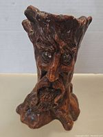 Frontal view of the detailed face vase showing beard, eyes, and textured bark-like surface