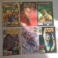 Photo showing front covers of six assorted comic books including 'War of the Worlds', 'Dark Avengers: Ares', 'Captain America: Theater of War', 'Black Knight', 'Demon Days', and 'Die Cut'.