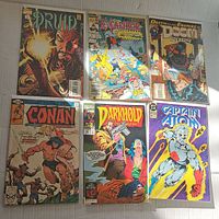 Photo shows 6 comic books: Druid, Excalibur, Doctor Doom 2099, two Conan issues, Darkhold, and Captain Atom with colorful illustrated covers.
