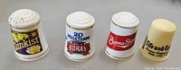 Four vintage advertising thimbles featuring Sunkist, 20 Mule Team Borax, Burma-Shave, and Life and Cook brands.