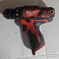 Side view of Milwaukee 3/8 cordless drill driver showing brand logo, red and black color, and torque setting dial