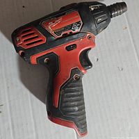 Side view of red and black Milwaukee cordless screwdriver drill showing worn grip and nameplate