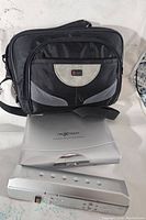 Black and gray carrying case with Nexxtech DVD player and detachable battery pack placed in front of it, shown on a white surface.