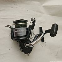 Side view of Shimano Sienna 4000FE spinning reel showing overall condition and silver spool with green fishing line.