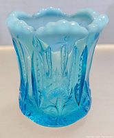 Front angled view of vintage blue opalescent glass toothpick holder showing detailed embossed floral and leaf design and scalloped top edge