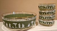 Six green Wedgwood bowls including one large and five smaller stacked bowls featuring white Hellenic Greek classical figure relief decoration and gold rims.