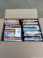 Open box filled with 75 DVD cases stacked neatly showing various movie titles