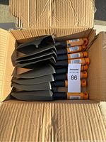 Box containing 8 Fiskars FiberComp trowels with black blades and orange handle ends, stacked inside a cardboard box.