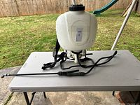 Photo of sprayer showing full tank, hose extended with spray wand.