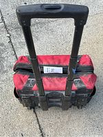 Red Husky rolling tool bag with extendable handle, viewed from top showing bag and handle.