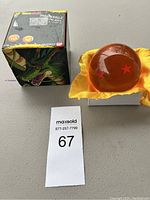 Photo of the Dragon Ball Z four-star Dragon Ball collectible orb, its yellow display cloth, and original box with dragon artwork.