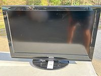 Front view of Dynex LCD TV showing screen, bezel, and stand with lot tag.