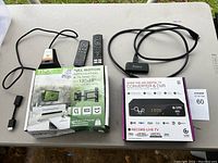 TV wall mount box, two remotes, digital TV converter box, and an HDMI cable shown on a gray table.