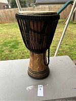 Full view of the djembe drum showing wood carvings and rope tensioning