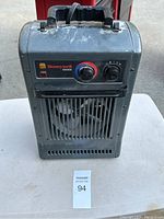 Front view of a gray portable Honeywell electric heater showing the control panel with two knobs and a carrying handle on top.