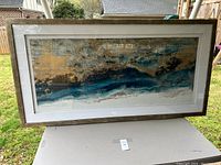 Full view of the large framed artwork showing abstract textured design in blue, tan, and white within a wooden frame.