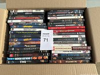 Top-down view of a box filled with 75 DVDs stacked vertically showing assorted movie titles