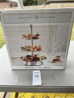 Box showing brand 'Bella Cucina Artful Food' and product name 'Rotating 3-Tier Platter'.