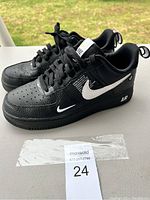 Pair of black Nike Air sneakers, size 7.5, displayed from the lateral side showcasing perforated leather and white swoosh logo.
