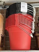 Stacked plastic buckets including black and red, metal handles visible, stacked inside each other.