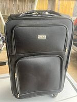Front view of the large black Wang Gilda suitcase showing two zippered pockets and handle.