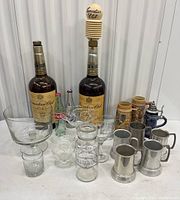 Photo showing two large Canadian Club liquor bottles, one filled with bottle caps, surrounding glassware, and ceramic stein mugs.