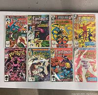 Eight Marvel Fantastic Four comics in plastic sleeves arranged in two rows of four on a table, showing front covers including titles and colorful artwork.