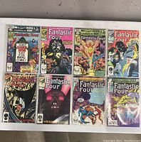 Photo showing front covers of 8 Fantastic Four comic books in plastic sleeves, arranged in two rows of four, showcasing colorful and dynamic cover art.