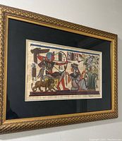 Framed Egyptian art hung on a wall featuring traditional Egyptian figures and motifs.