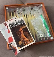 Top view of the wooden game set with glass chess board, frosted and clear glass pieces placed on board, accompanied by two paperback chess books
