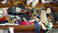 Top view of drawer filled with assorted vintage belts of various colors, materials and buckle styles.