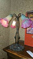 Full view of the Dale Tiffany style lamp showing five lily-shaped glass shades in pink and light green with a curved metal stem and decorative base.