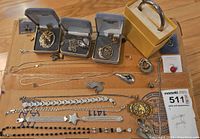 Overview of all sterling silver jewelry laid out on cardboard, including boxed pendants, bangle, chains, earrings, bracelets, red pin
