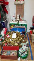 Overall view showing various holiday decorations including gold tinsel garland, figurines, nativity set, and Putz houses alongside boxed Econolite light.