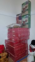 Photo of stacked sealed Vogart Crafts crochet kits including red boxes and green/white vintage package with crochet animal kits