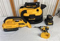 All five items displayed on table: vacuum units, impact driver, battery and charger showing overall lot contents.