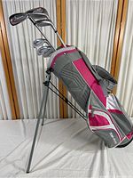 Full view of Top-Flite junior golf clubs in pink and gray club bag with stand deployed.