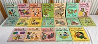 Full set of 19 Walt Disney Fun To Learn books displayed on a table, showing cover art and titles.