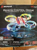 Front of box showing BEZGAR branding, model HQ051, age recommendation 14+, and drone image with ringed propellers in red, blue, and white colors.