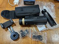 Complete lot including Joker monocular, tripod, carrying case, mount, and accessories on a wooden surface with box and charger visible.