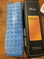 Blue heating pad with soft textured surface and original packaging box labeled 'Climate Multifunctional Electrical Heating Pad'