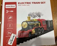 Close-up of the box front showing the train set name, brand Lucky Doug, and features like spray, sound and light with age recommendation 3+
