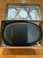 Top view of Kataysymbol label maker device in its box with extra label tape in sealed packaging above it.