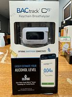 BACtrack C6 Keychain Breathalyzer in original packaging showing the device and smartphone connectivity feature.