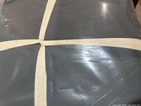 Photo showing close-up of dark grey sheets wrapped in clear plastic packaging.